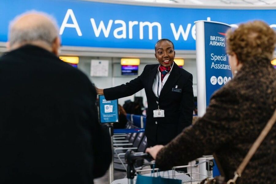 A British Airways employee assists passengers with check in