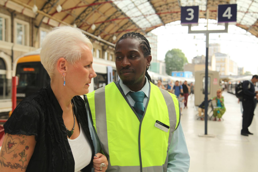 Karen on a train platform being aided by a staff member